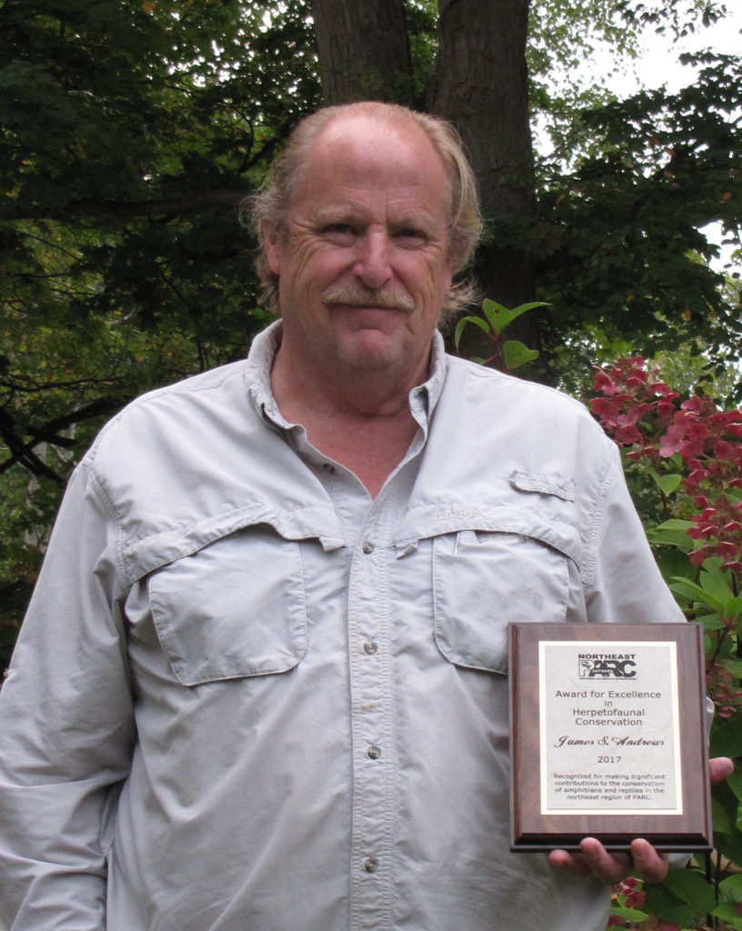 Jim Andrews holds a plaque of recognition.