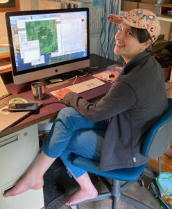 a woman sits in a chair in front of a computer smiling